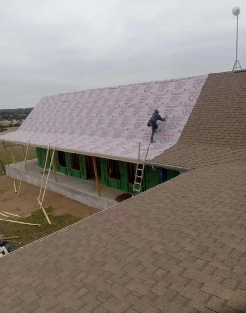 Worker preparing underlayment for a metal roof installation in Penfield
